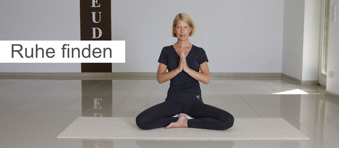 Foto im Slider, Motiv: Yogalehrerin im Lotussitz Hände zum Namaste, Titel: Ruhe finden